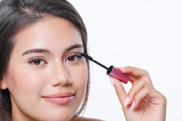 Young female with compact mirror in hand applying eyeliner during daily beauty procedure at home