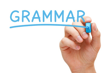 Hand writing Grammar with blue marker on transparent glass board.