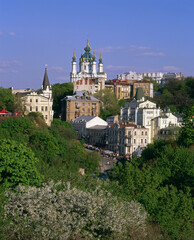 Fototapeta na wymiar Andriyivskyy Descent and the Saint Andrew's Church with blossom trees in foreground. Kiev.