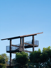 Fototapeta premium Metal structured bird watching tower surrounded by big trees.