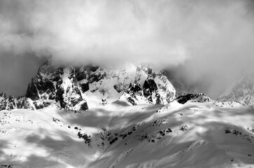Black and white view on Mount Ushba in fog at sun winter day. Caucasus Mountains. Svaneti region of Georgia.