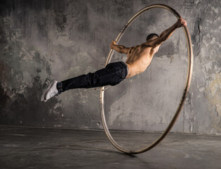 Strong circus performer spinning a cyr wheel