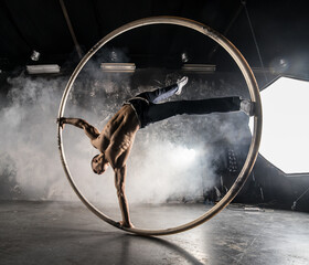 Strong circus performer spinning a cyr wheel