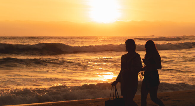 Personas a contraluz disfrutando de las olas del mar en la hora dorada, nadando, corriendo. atardecer, sunset, concepto de atardeceres de verano en la playa.