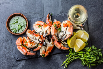 Seafood. Crabs tentacles on black plate with wite wine, lemon and herbs sauce on slate background....