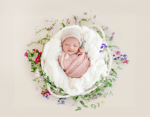 Sleeping newborn baby girl wrapped in a basket with flowers