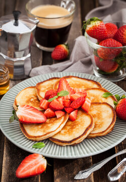 Homemade delicious pancakes served with fresh strawberries and honey for breakfast