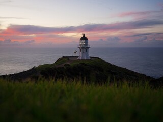 Panoramic view of historic white Cape Reinga lighthouse landmark on oceanside clifftop during...