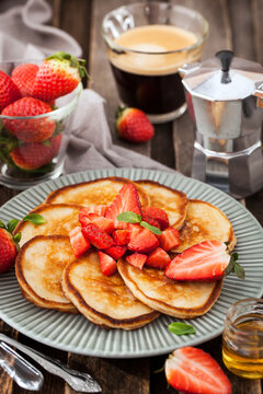 Homemade delicious pancakes served with fresh strawberries and honey for breakfast