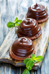 Wooden stand with cakes with souffle in chocolate glaze and mint, selective focus.