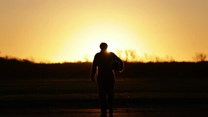 Silhouette of an Air Force Pilot Walking With His Flying Helmet During Sunset at Air Base. 4K Resolution.