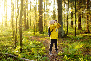 Little boy scout with binoculars during hiking in autumn forest. Child is looking with binoculars. - obrazy, fototapety, plakaty
