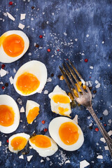 Fototapeta na wymiar Hard boiled eggs, sliced in halves on wooden painted table