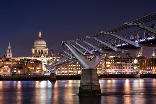 St Paul's Cathedral and the Millennium Bridge over the Thames, at night, with the lights shining on the opposite shore