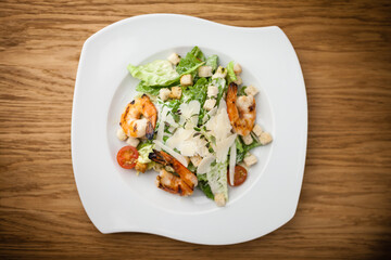 Fototapeta na wymiar Caesar Salad with shrimps served on a plate in restaurant