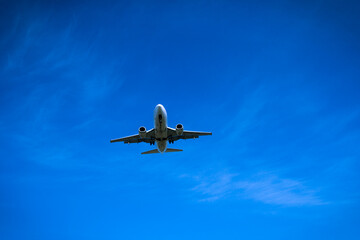 Fototapeta na wymiar Jet airplane flying overhead close-up on a blue sky background
