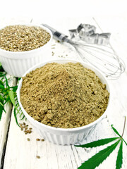 Flour and hemp grain in white bowls, mixer and cookie cutters, cannabis leaves on the background of wooden boards