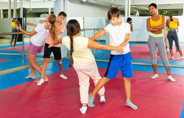 Fototapeta na wymiar Sporty girls and boys are practices self-defence moves in pairs in sporty gym
