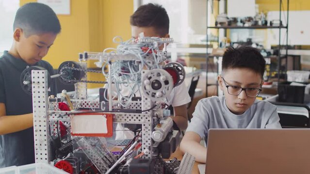 Group of multinational schoolchildren working on laptop, studying and programming at robotics engineering class. School classroom of futuristic technologies