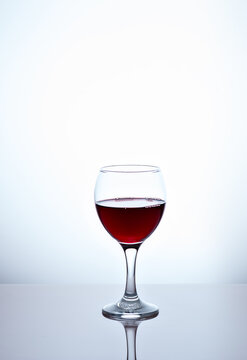 One glass filled with half red wine