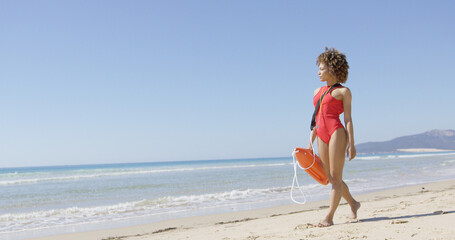 Lifeguard female with rescue float walking on beach and looking into distance. Tarifa beach. Provincia Cadiz. Spain.