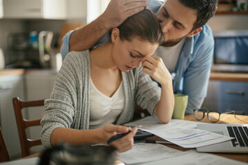 Young couple going over their bills at home in the kitchen