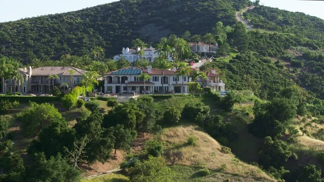 Drone shot of beautifully appointed private mansion surrounded with lush greenish mountains. Amazing high-end residential house settled on top of a grassy area. High quality 4k footage