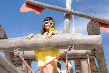 A girl playing outdoors at the playground in the park on a hot summer day. children's playground in a public park, entertainment and recreation for children, mountaineering training.
