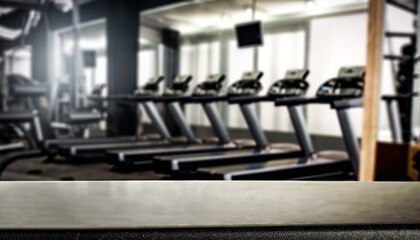 Black desk of free space for your decoration and blurred gym interior. Metal dumbbells and fit life
