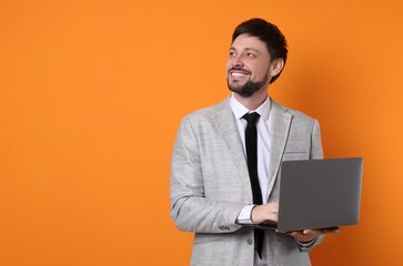 Happy man with laptop on orange background, space for text