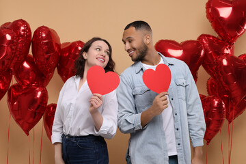 Lovely couple with red paper hearts on beige background. Valentine's day celebration