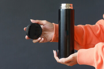 Closeup hand holding aluminium reusable steel stainless eco thermo water bottle with mockup,...