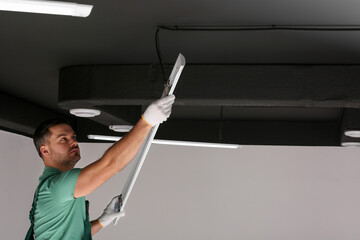 Ceiling light. Electrician installing led linear lamp indoors. Space for text