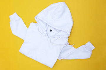 White color hoodie top view on yellow background. 