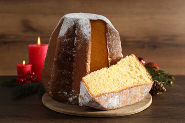 Delicious Pandoro cake with powdered sugar and Christmas decor on wooden table. Traditional Italian...