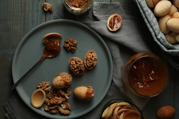 Fototapeta na wymiar Freshly baked homemade walnut shaped cookies with nuts and boiled condensed milk on wooden table, flat lay