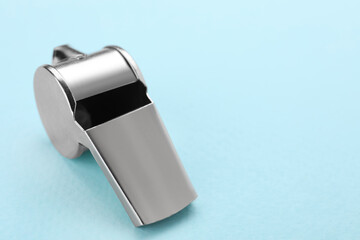 One metal whistle on light blue background, closeup. Space for text