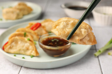 Taking delicious gyoza (asian dumpling) from plate at table, closeup. Space for text