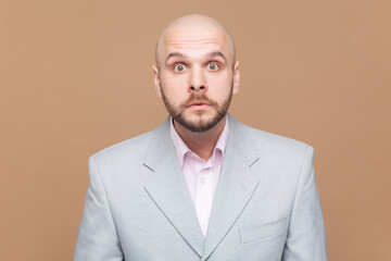 Portrait of shocked startled bald bearded man stares bugged eyes at camera hears big news, feels...