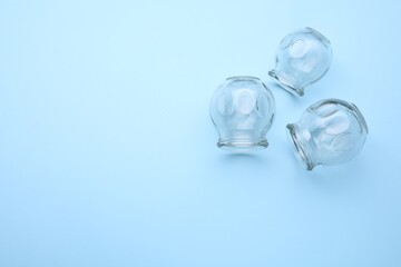 Glass cups on light blue background, flat lay with space for text. Cupping therapy