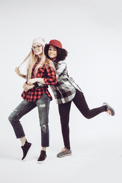 Studio lifestyle portrait of two best friends hipster girls wearing stylish bright outfits, going crazy and having great time together. Isolated on white background.