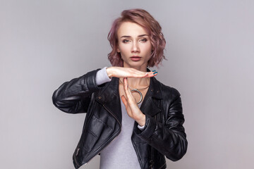 Portrait of adorable sad woman with short hairstyle standing showing time out gesture, needs more...