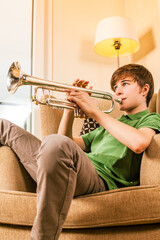 Photo of a teenage male practicing his trumpet at home. © Designpics