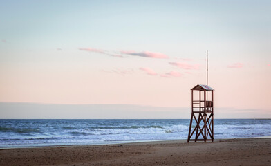 Mediterranean beach sunrise with vintage and lonely lifeguard wooden tower