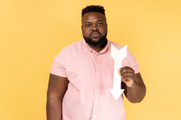Portrait of sad upset depressed bearded man wearing pink shirt showing white arrow pointing down,...