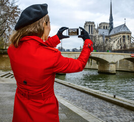 Bright in Paris. Seen from behind trendy traveller woman in red trench coat on embankment near...