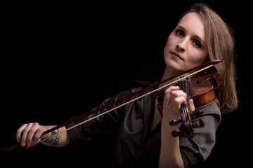 Young beautiful woman violinist player  looking at camera over instrument on her shoulder holding...