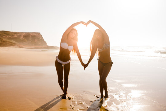 Beautiful girls in the beach making hearts with their arms
