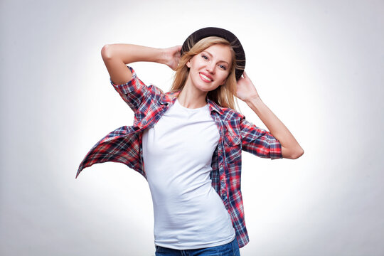 Closeup fashion studio portrait of hipster young smiling woman in black hat and denim vest over light grey background
