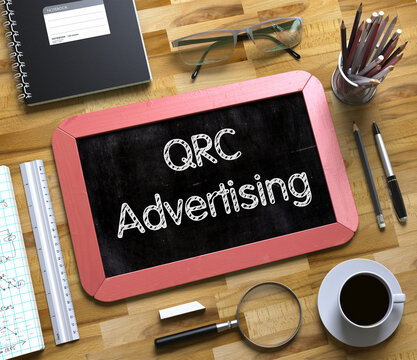 QRC Advertising on Small Chalkboard. QRC Advertising Handwritten on Red Chalkboard. Top View Composition with Small Chalkboard on Working Table with Office Supplies Around. 3d Rendering.